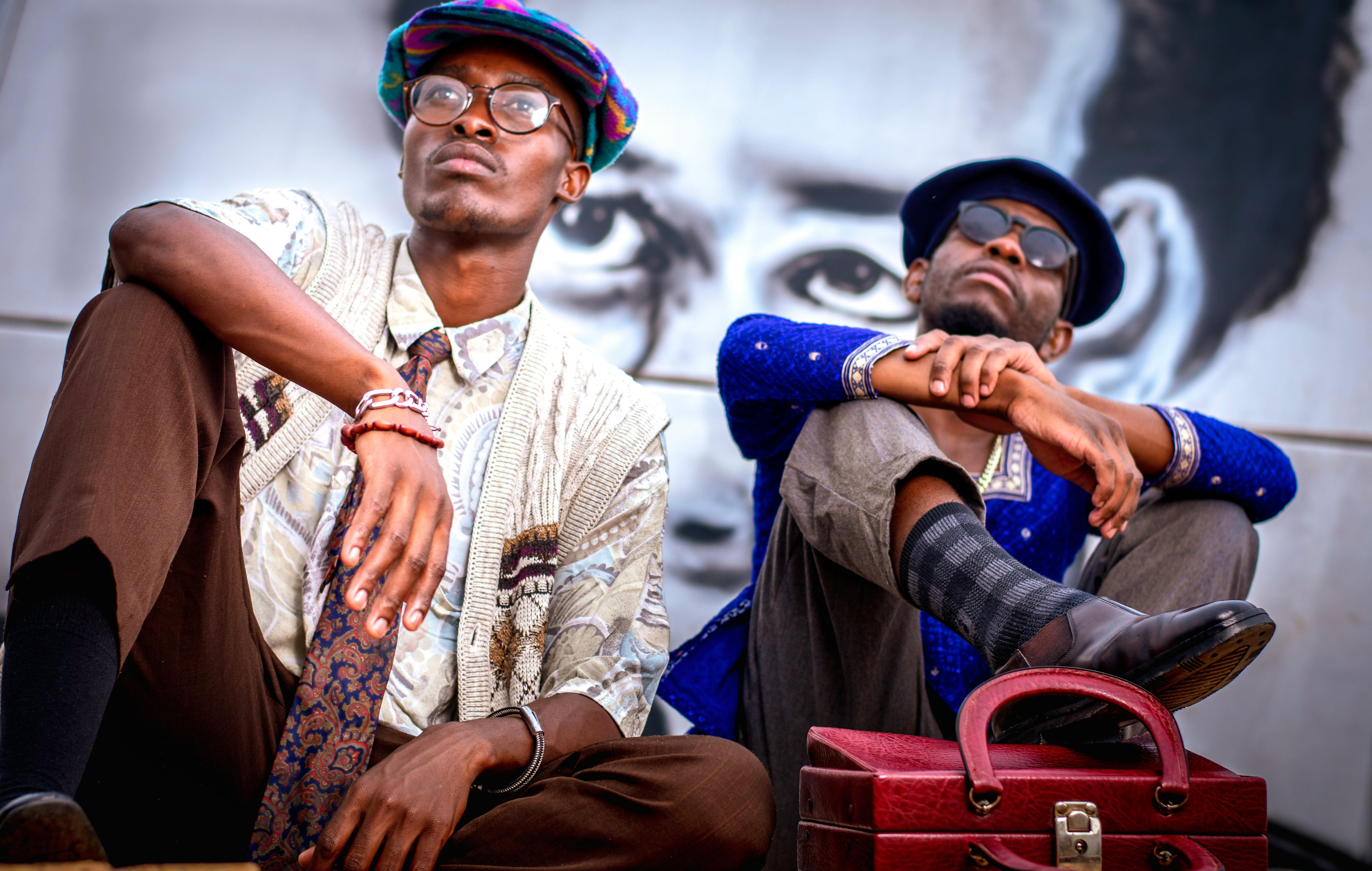 两名时尚男子在城市环境中自信地对着壁画摆姿势