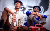 两名时尚男子在城市环境中自信地对着壁画摆姿势