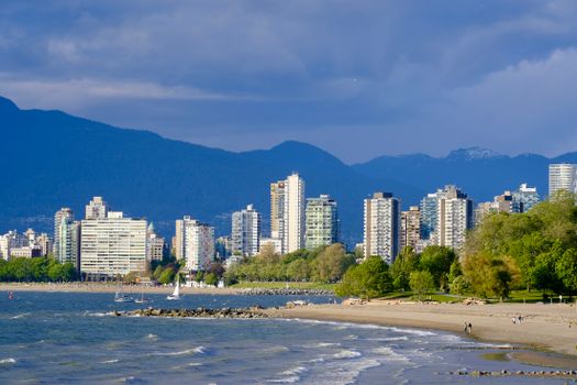Vancouver's skyline from the beach with water and mountains in view.