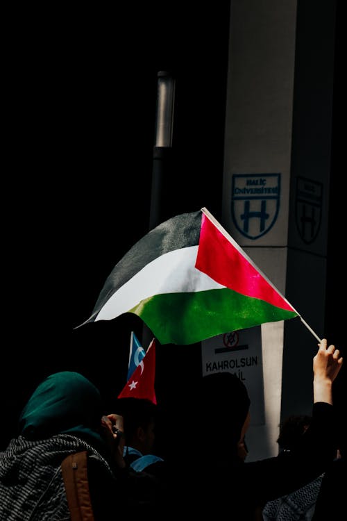 A person holding a palestinian flag in front of a building