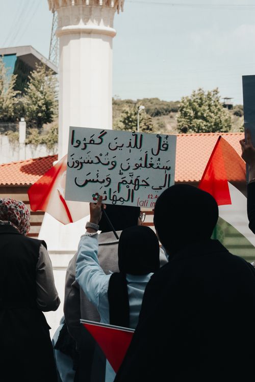 Free Women in hijabs hold a sign and Palestinian flags in a peaceful street demonstration. Stock Photo