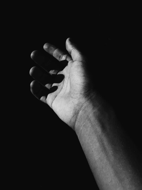 Free High-contrast monochrome photo of an open hand against a dark background. Stock Photo