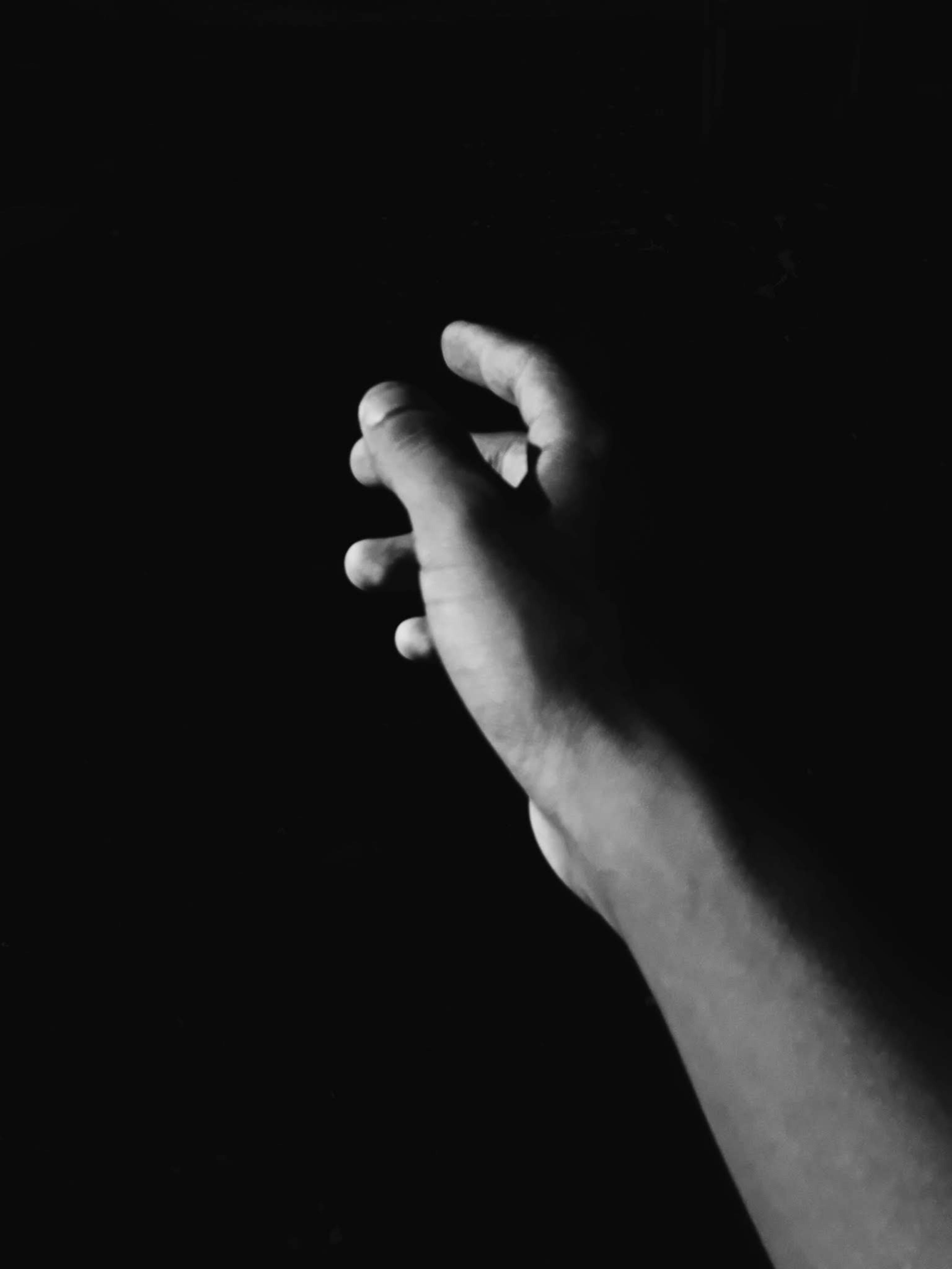 Grayscale Photo of Hand Reaching Out Against Black Background · Free