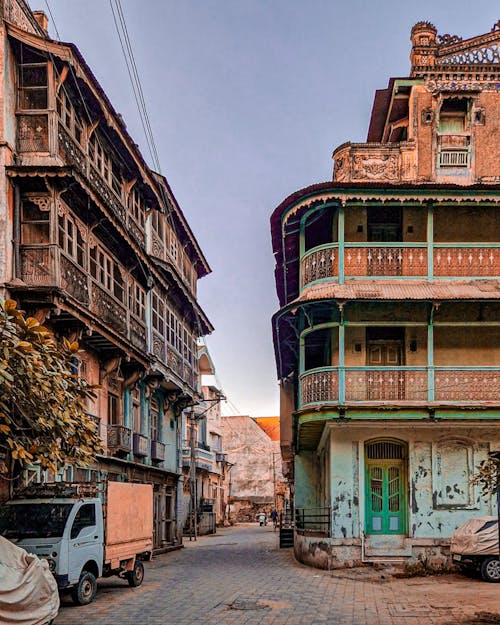 A street with two old buildings and a car parked in front of them