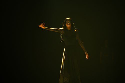 Free A dramatic, high-fashion pose in a dimly lit studio with a woman in a black dress, evoking mystery. Stock Photo