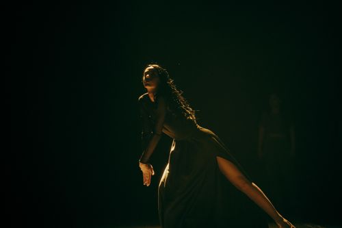 Free Artistic dance pose captured in a dark studio with dramatic lighting and a black dress. Stock Photo