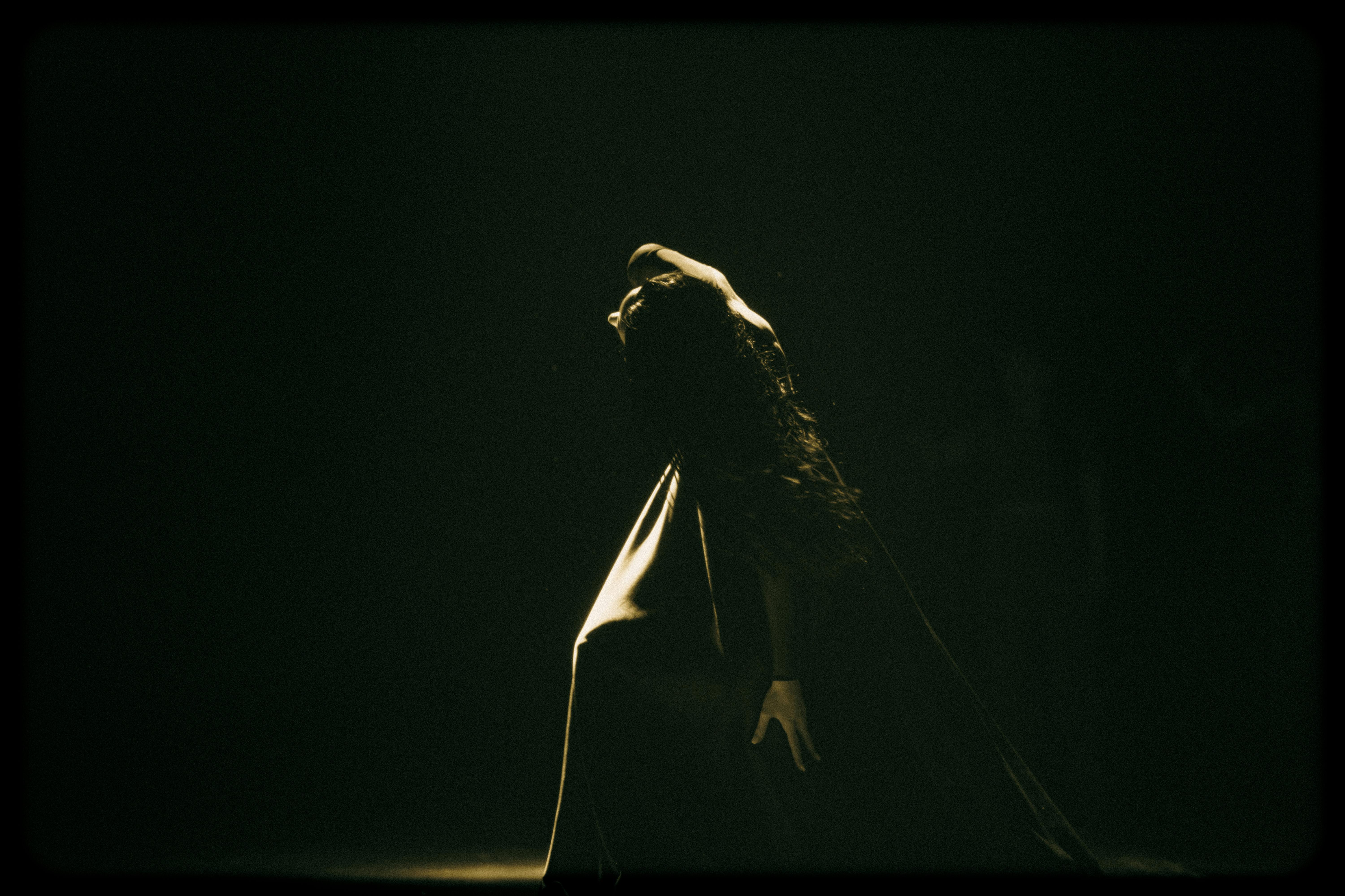 Free Artistic studio portrait of a woman bending backward, captured with dramatic lighting. Stock Photo