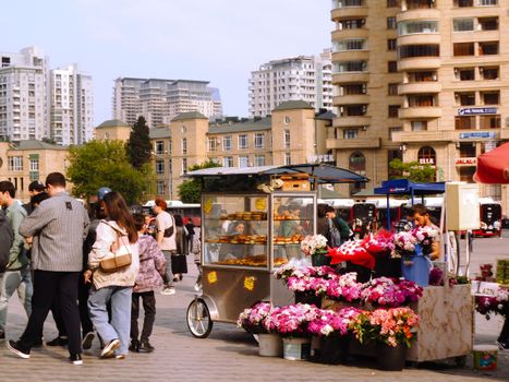 Busy urban street scene in Baku featuring street vendors and high-rise buildings.