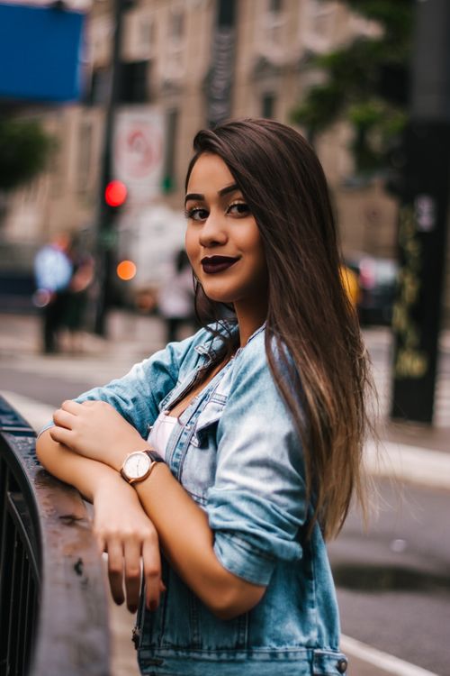 Free Stylish woman in denim poses happily by a railing in bustling São Paulo street. Stock Photo