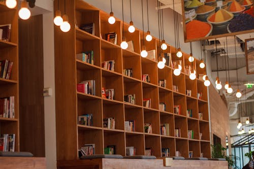 Книги внутри книжной полки возле освещенных подвесных светильников