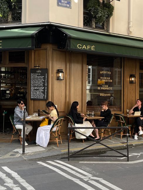 A lively Parisian sidewalk café with people enjoying the ambiance and street life.