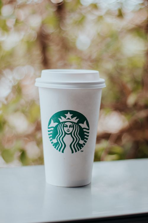 Free Close-up of a Starbucks disposable coffee cup on a table, with a blurred background outdoors. Stock Photo