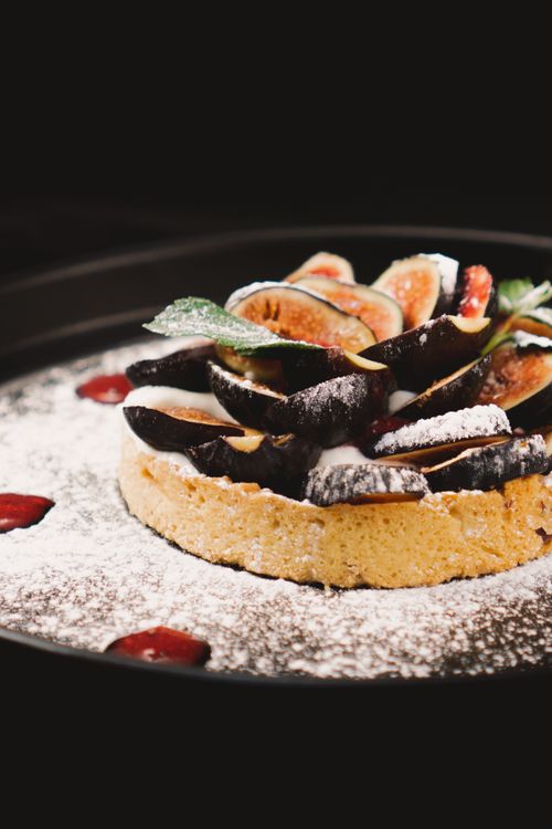 Free Artistic close-up of a fig tart dusted with powdered sugar, capturing its enticing texture and colors. Stock Photo