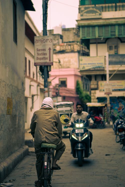 Free A lively street in Varanasi, India, showcasing local life with riders and motor scooters. Stock Photo