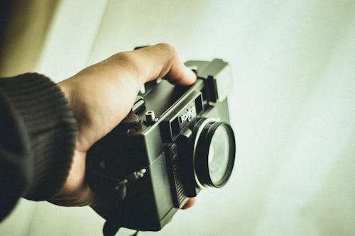 Close-up Photo of Person's Hand Holding Black Konica C35 Camera