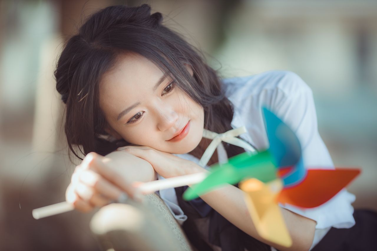 asian woman enjoying a colorful pinwheel capturing a moment of serenit