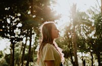 一位年轻女子闭着眼睛，在户外阳光下享受平静的时刻