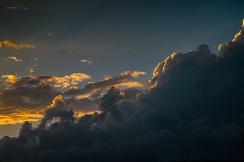 Free Majestic clouds with golden sunset highlights create a dramatic sky view. Stock Photo