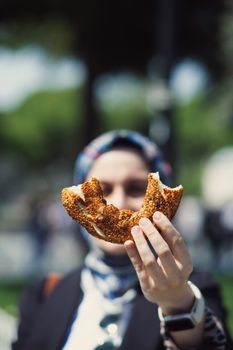 Close-up of a woman holding a Turkish simit outdoors in Istanbul.