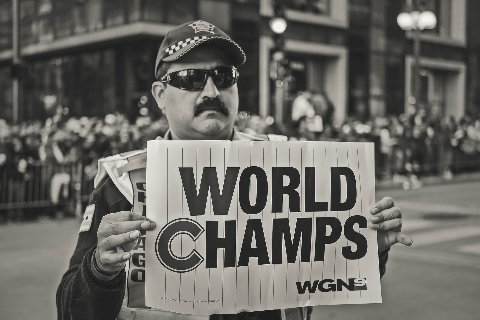 A man holds a 'World Champs' sign during a celebratory parade. Monochrome image.