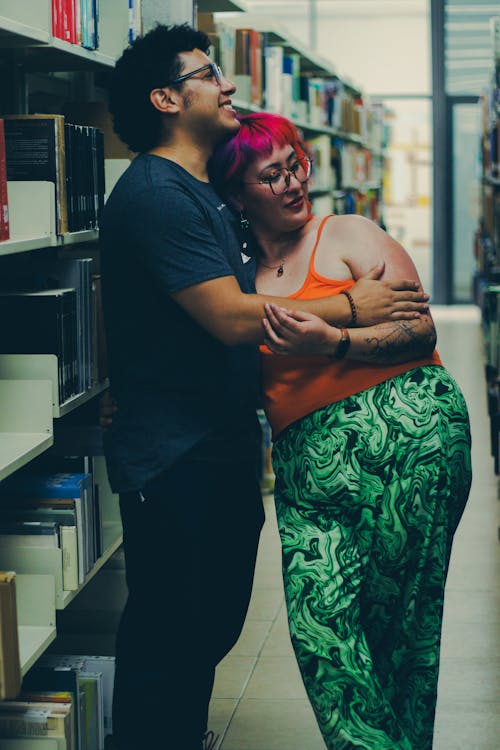 A couple hugging in a library with books