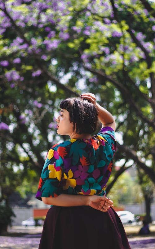 A woman in a colorful top and skirt standing in front of a tree