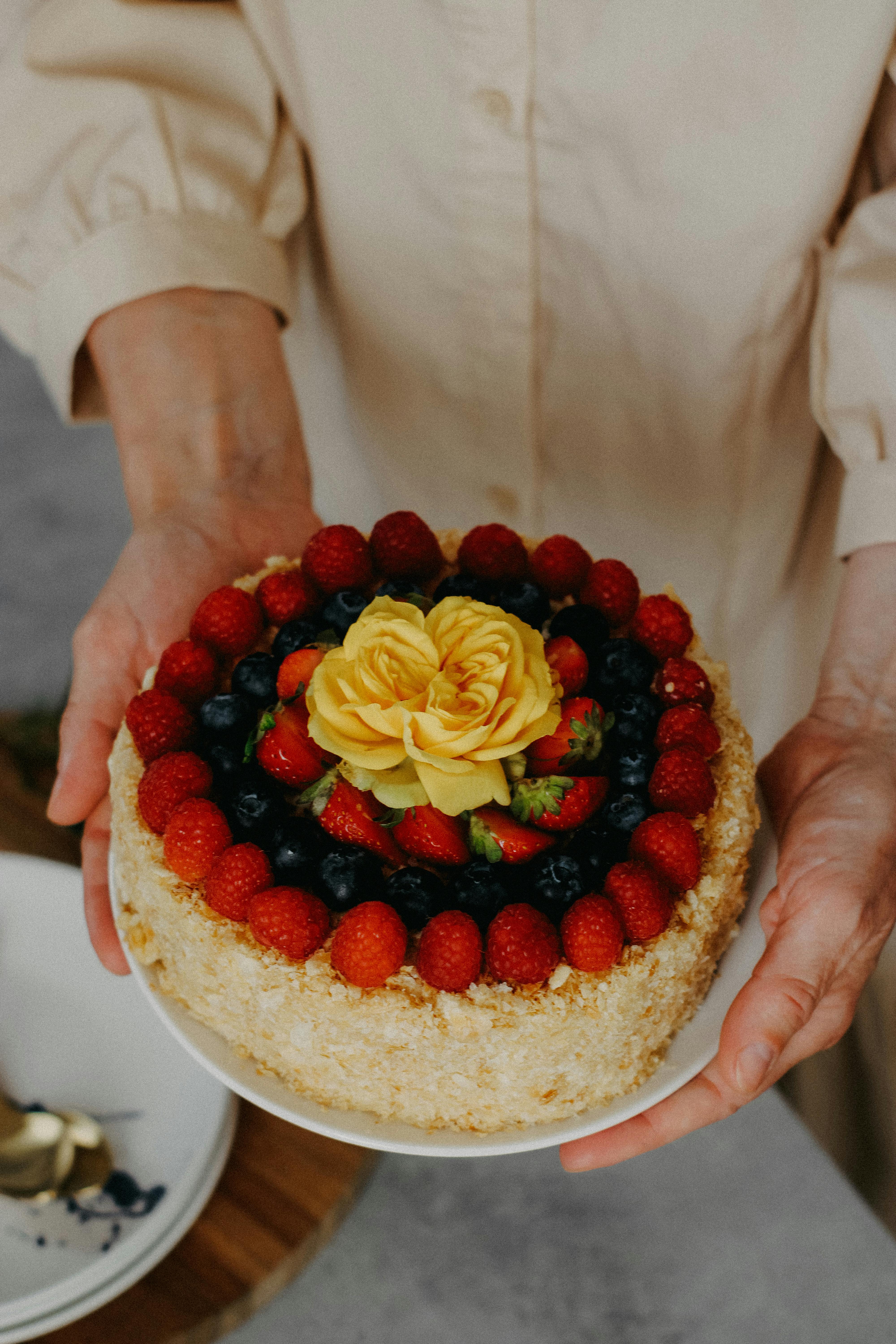 Handheld berry cake with a yellow flower topping, perfect for celebrations.