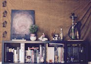 书架上摆放着书籍、小雕像、艺术品和水烟，背景有图案