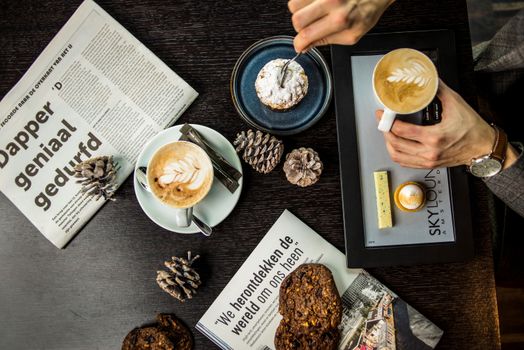 Top view of a stylish café table setup with cappuccinos and pastries, perfect for urban breakfast scenes.