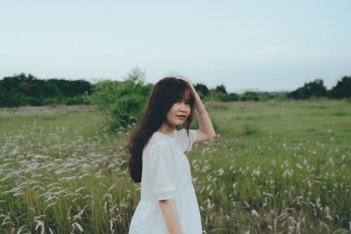 A woman in a white dress standing in a field