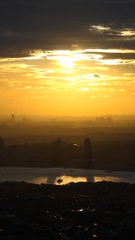 Stunning aerial view of a cityscape at sunset, highlighting silhouettes and a serene river.
