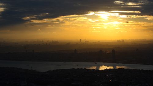 Free A stunning sunset over an urban skyline with silhouettes and river reflection. Stock Photo