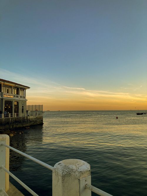 Free Beautiful sunset view over the sea with a building and railings in the foreground, capturing serene twilight vibes. Stock Photo