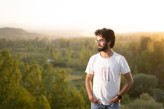A man in a white t-shirt enjoying the serene landscape of Srinagar at sunset.