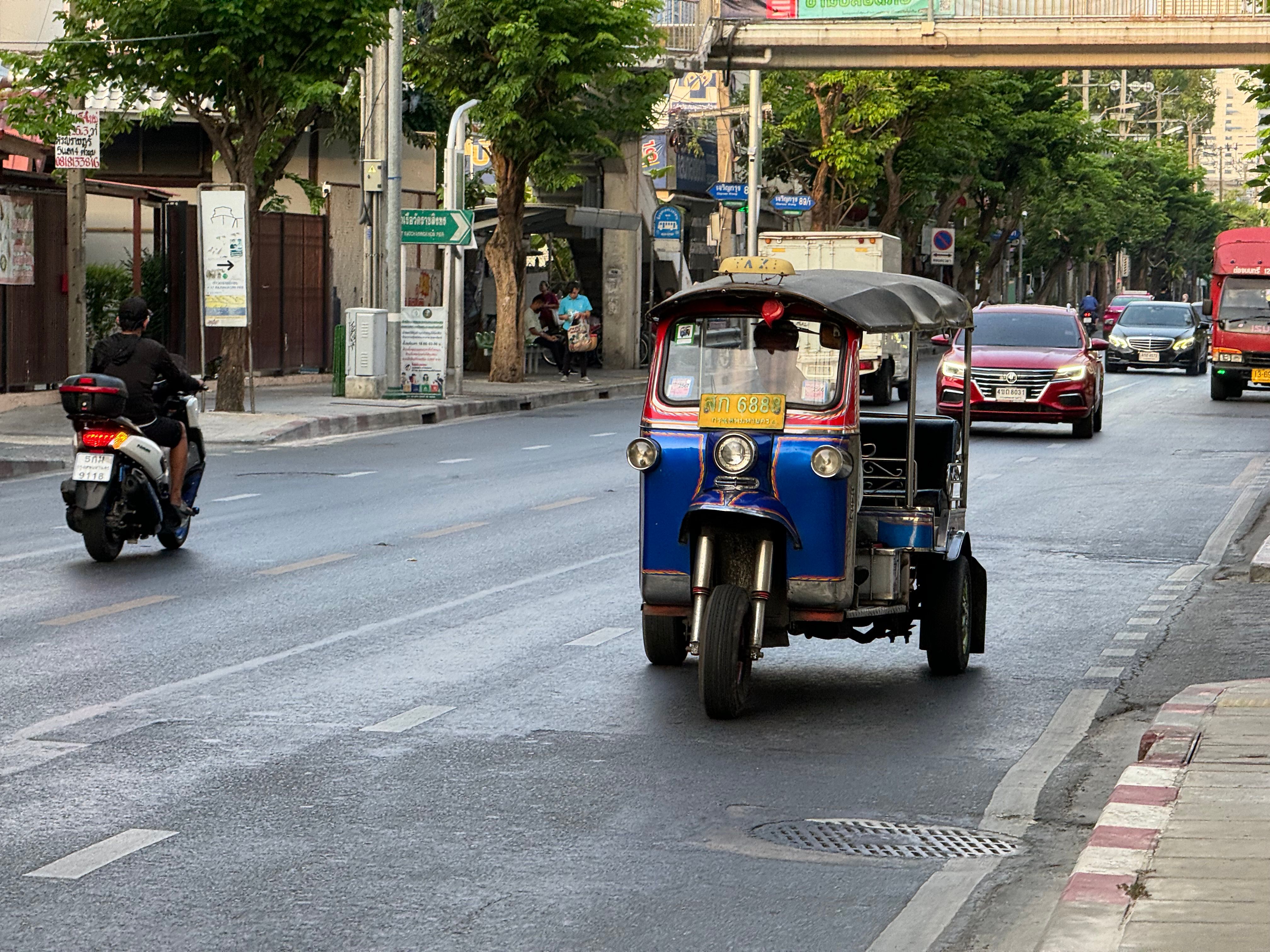 Tuk-tuk waiting for passengers on a Bangkok street, a common tourist-trap transport option in Southeast Asia