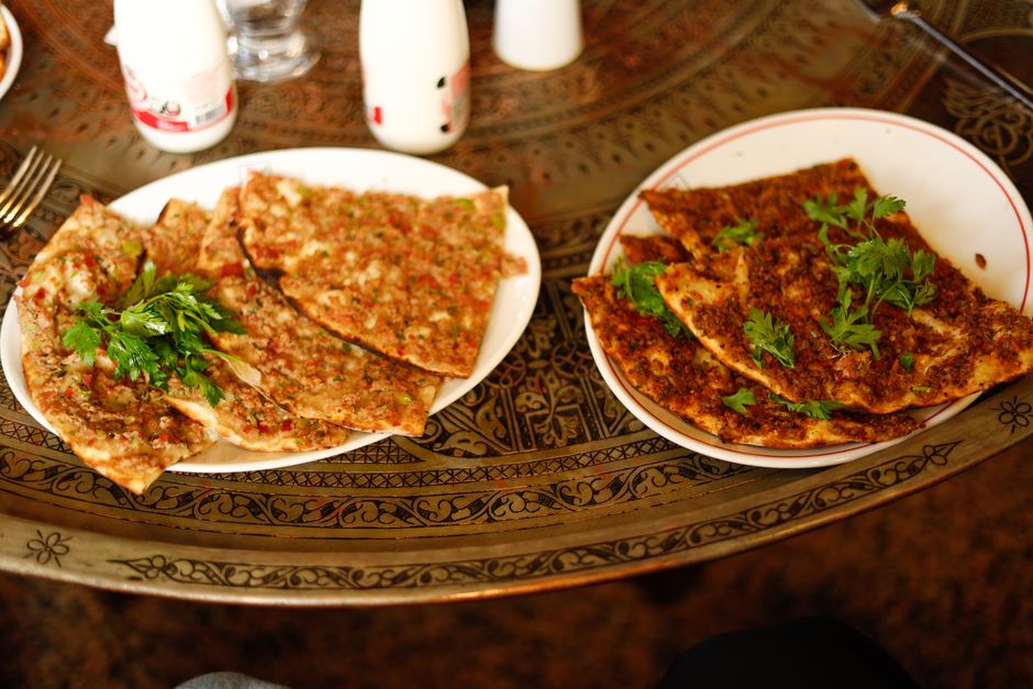 Top view of traditional Turkish lahmacun adorned with fresh parsley on an intricately designed table.