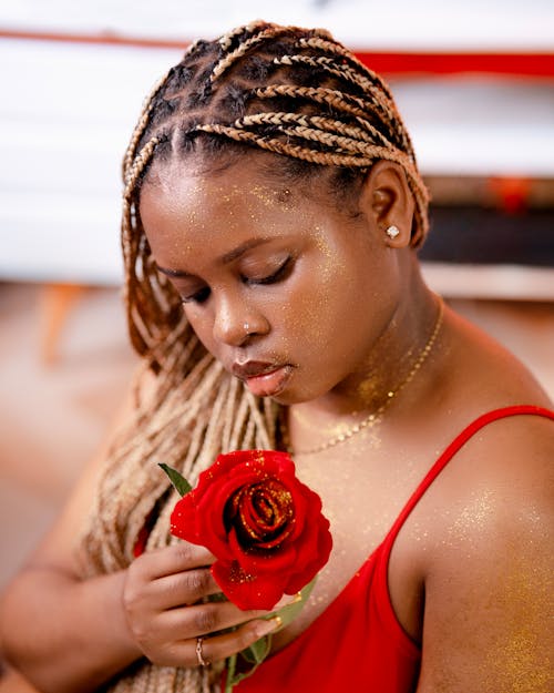 A woman with braids holding a red rose