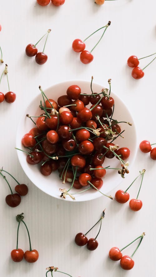 A bowl of cherries on a white table