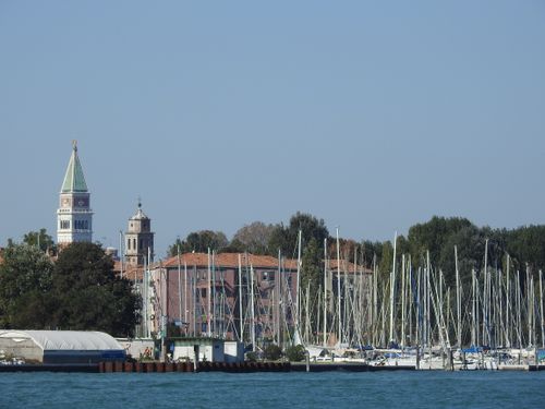 Free Captivating view of Venice with sailboats, lush greenery, and iconic bell towers under a clear blue sky. Stock Photo