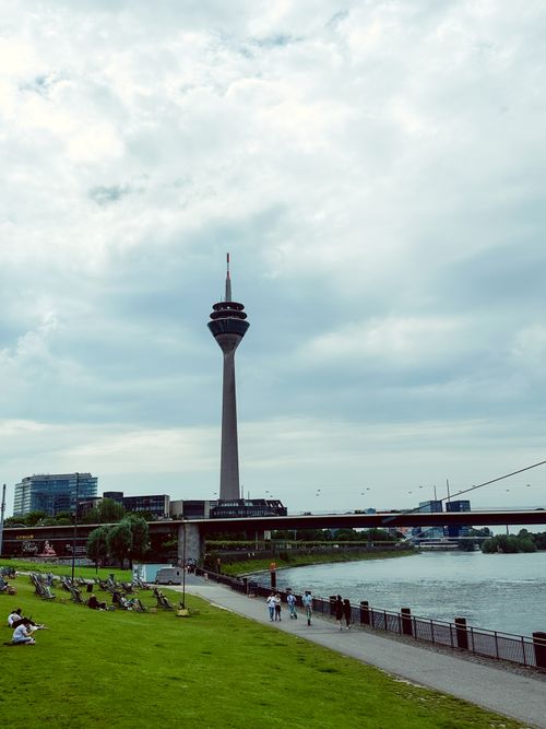 Free View of the Rheinturm tower in Düsseldorf by the Rhine River promenade on a cloudy day. Stock Photo
