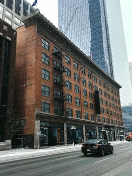 Old brick building with modern skyscraper background on snowy city street