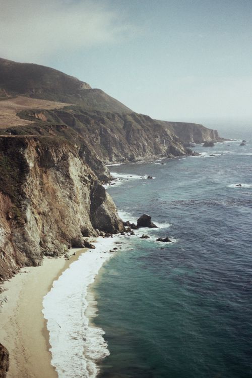 Free Stunning aerial view of rocky cliffs and coastline with the ocean waves crashing on the shore. Stock Photo