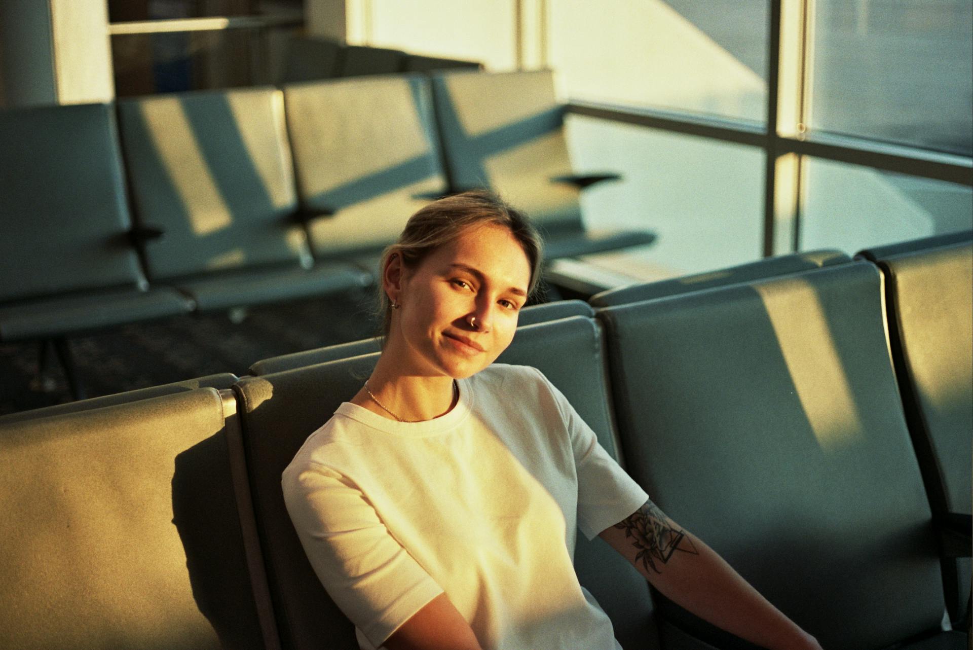 Smiling woman in an airport lounge seat, bathed in warm evening light.