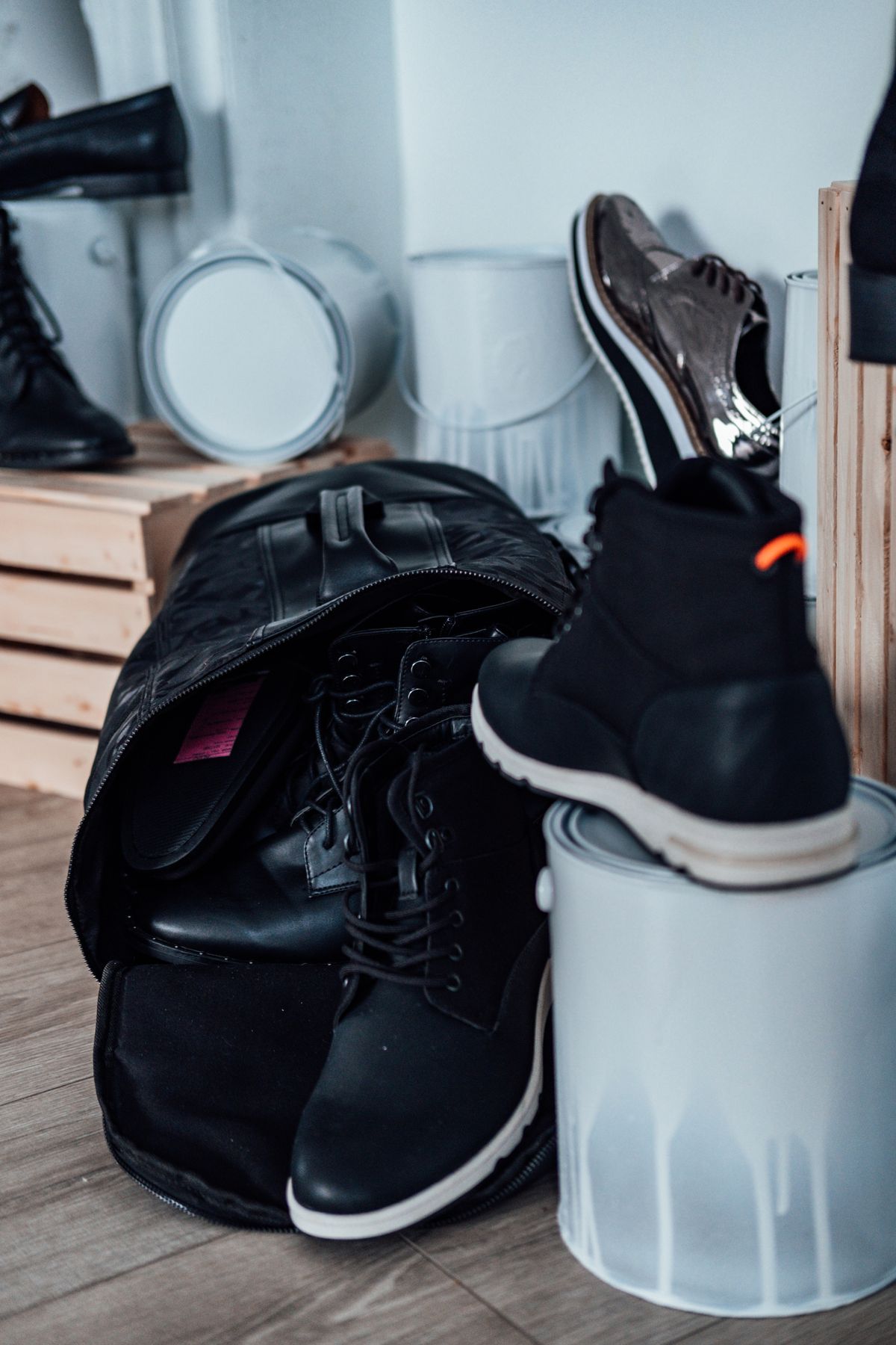 Black boots stored with a backpack and paint cans in a garage corner