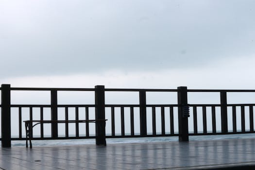 A peaceful wooden boardwalk overlooking the ocean on a cloudy day, perfect for reflection.