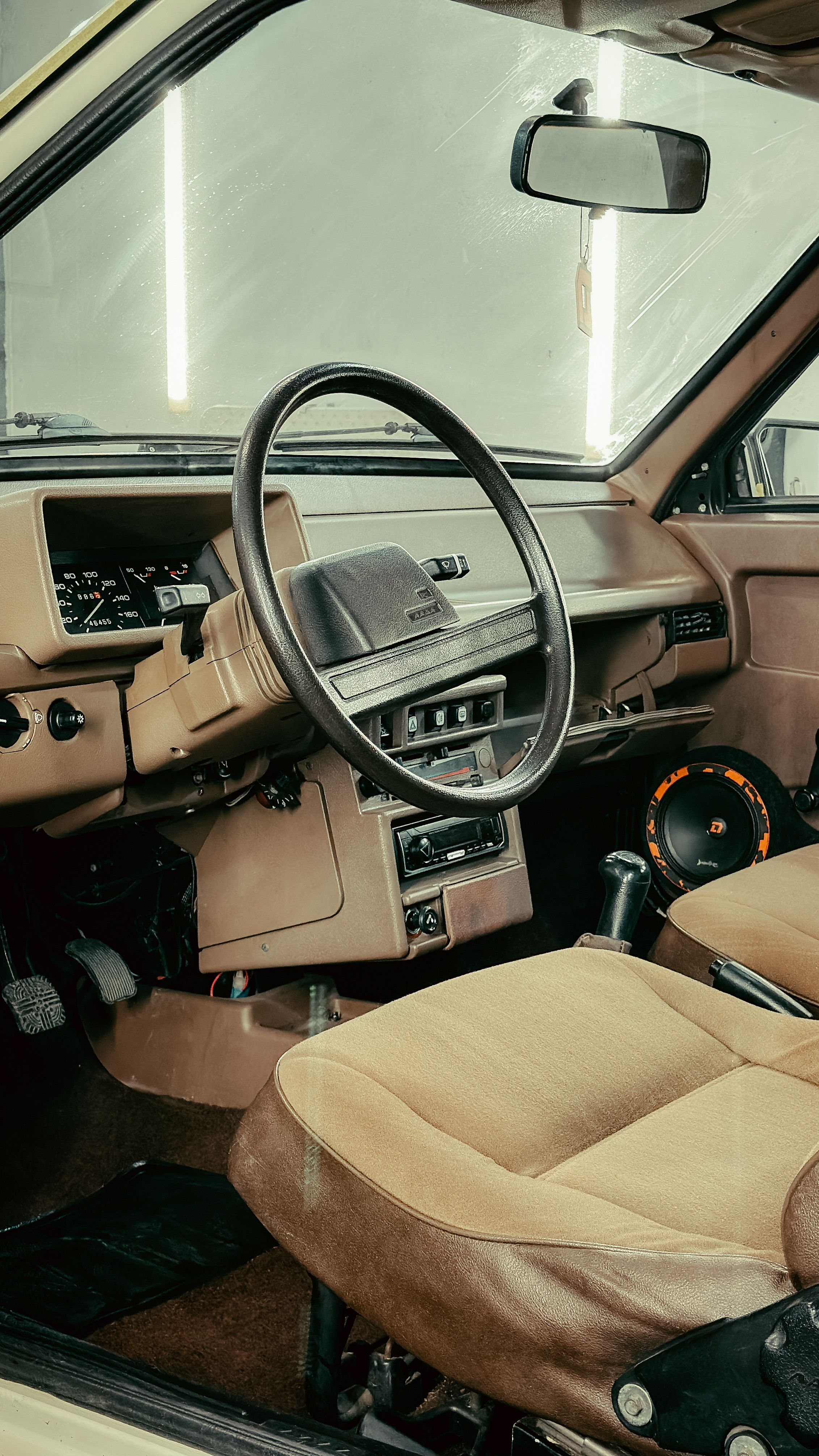 Detalhes de desgaste no volante, pedais e banco de um carro usado durante inspeção