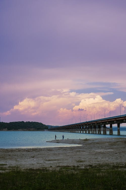 A bridge over a body of water with purple clouds