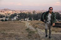 日落时分，在墨西哥乔卢拉，一名男子走过一片田野，田野上可见城市景观