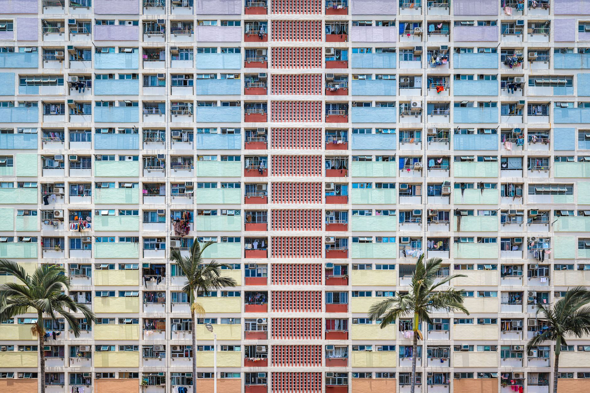 Vibrant facade of an apartment building in Hong Kong with palm trees in the foreground.