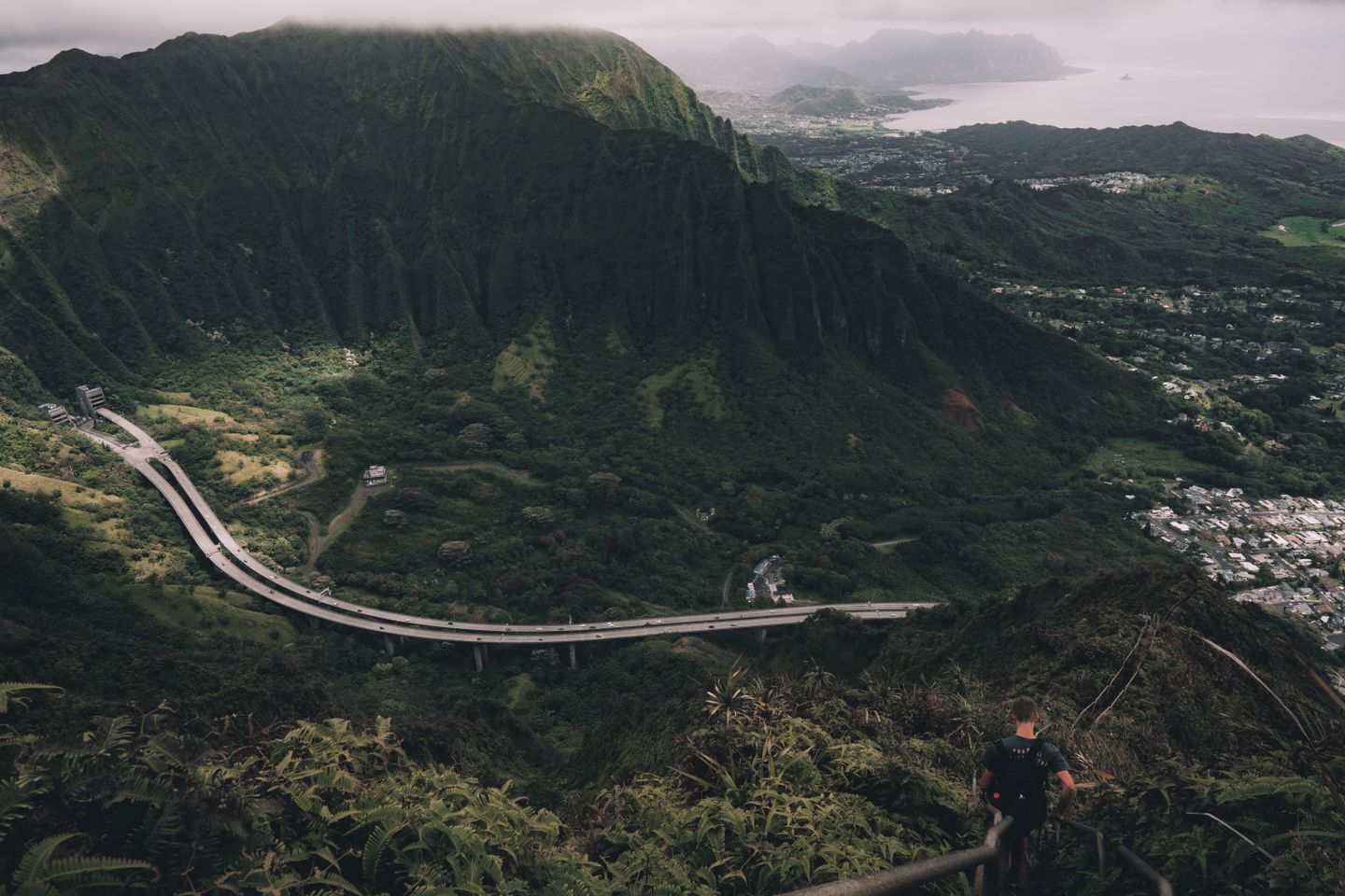 A narrow hiking trail along a green Hawaiian ridge with valley views